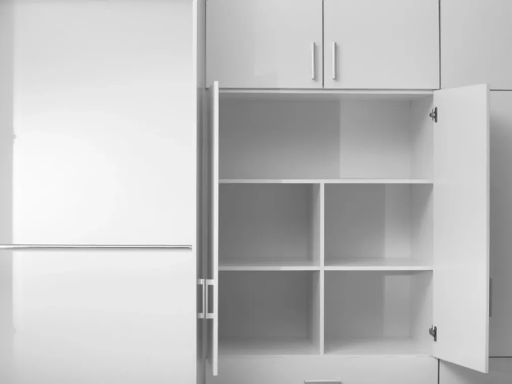 Biała szafa z otwartymi drzwiami, kwadratowymi przegródkami na półkach i drążkiem na wieszaki obok